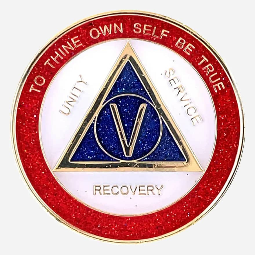 A dazzling AA sobriety medallion (approximately 34mm) with a gold-plated finish, featuring sparkling red, white, and blue enamel accents. The front prominently displays the AA circle and triangle symbol, surrounded by the words 'Unity,' 'Service,' and 'Recovery.' The outer rim is inscribed with 'To Thine Own Self Be True' and the sobriety anniversary year (in Roman numerals, 1-40 years). This token has a high-gloss, epoxy-coated finish that enhances its vibrant, glittery appearance.