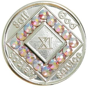 A silver colored coin with pink and white stones.
