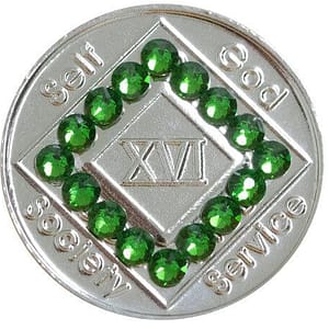 A silver colored medallion with green stones around it.