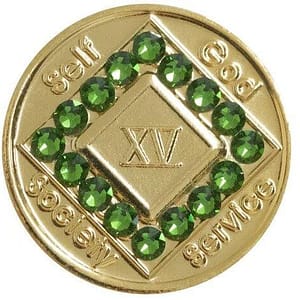A gold plated medallion with green stones in the center.