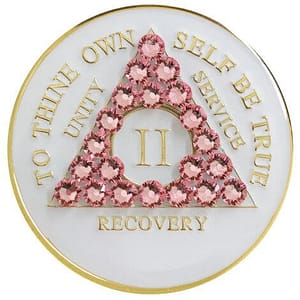 A white and gold coin with pink flowers on it.