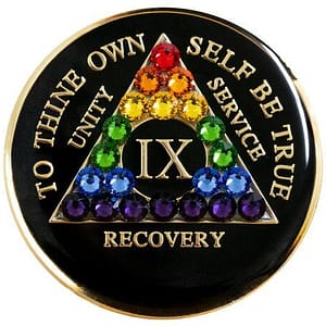 A black coin with rainbow colored stones in the center.