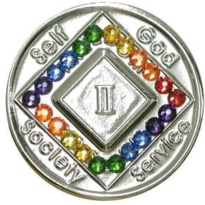A silver colored coin with rainbow colored stones.