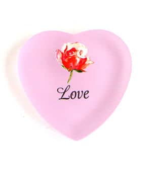 A pink heart shaped plate with the word love and a rose on it.