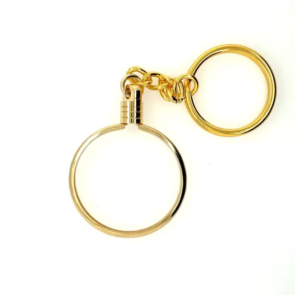 A gold key chain with a magnifying glass on it.