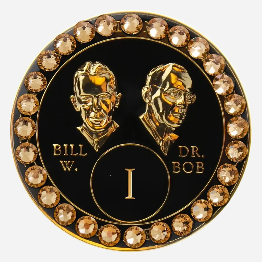 A black crystal AA medallion with gold accents, featuring stylized busts of Bill W. and Dr. Bob.