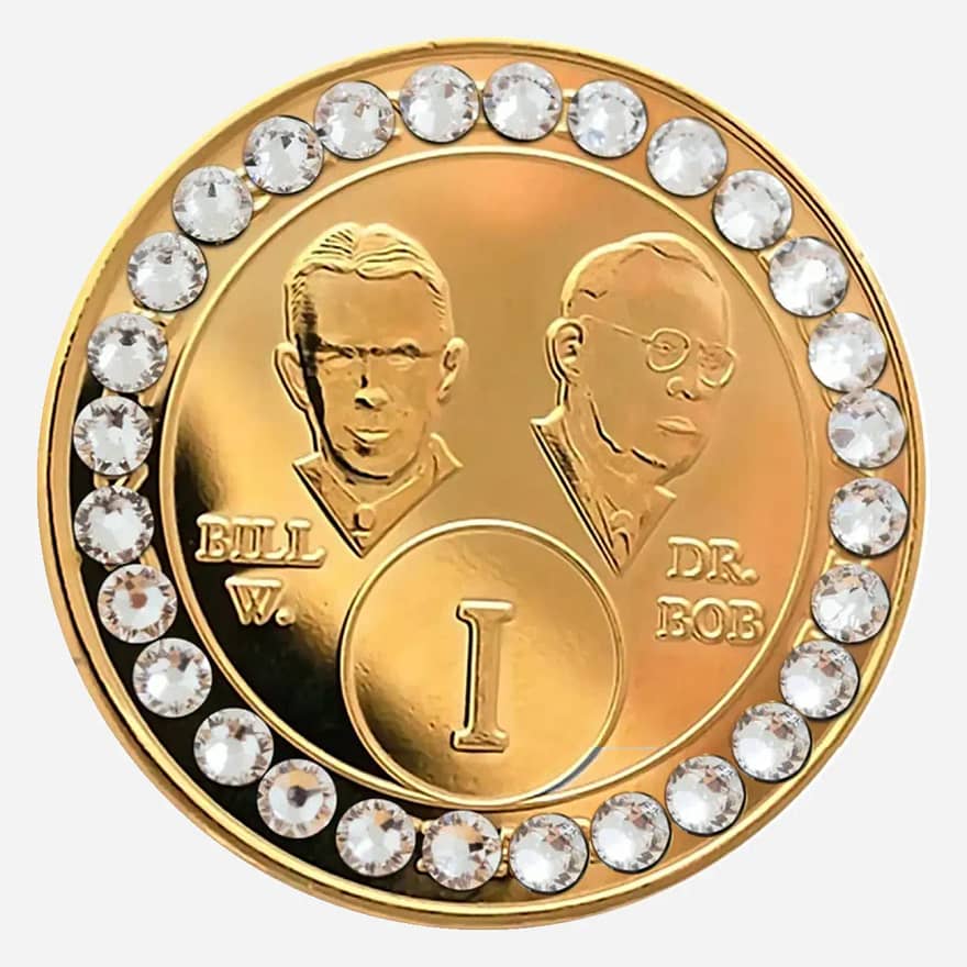 Gold AA medallion with diamond accents, featuring stylized busts of Bill W. and Dr. Bob, commemorating sobriety.