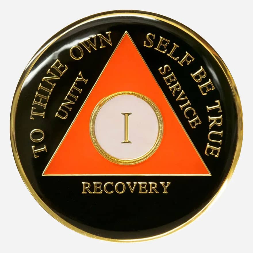 A striking orange AA symbol and motto pop against the black background of this Triplate AA Token, representing the energy and vibrancy of a life in recovery.