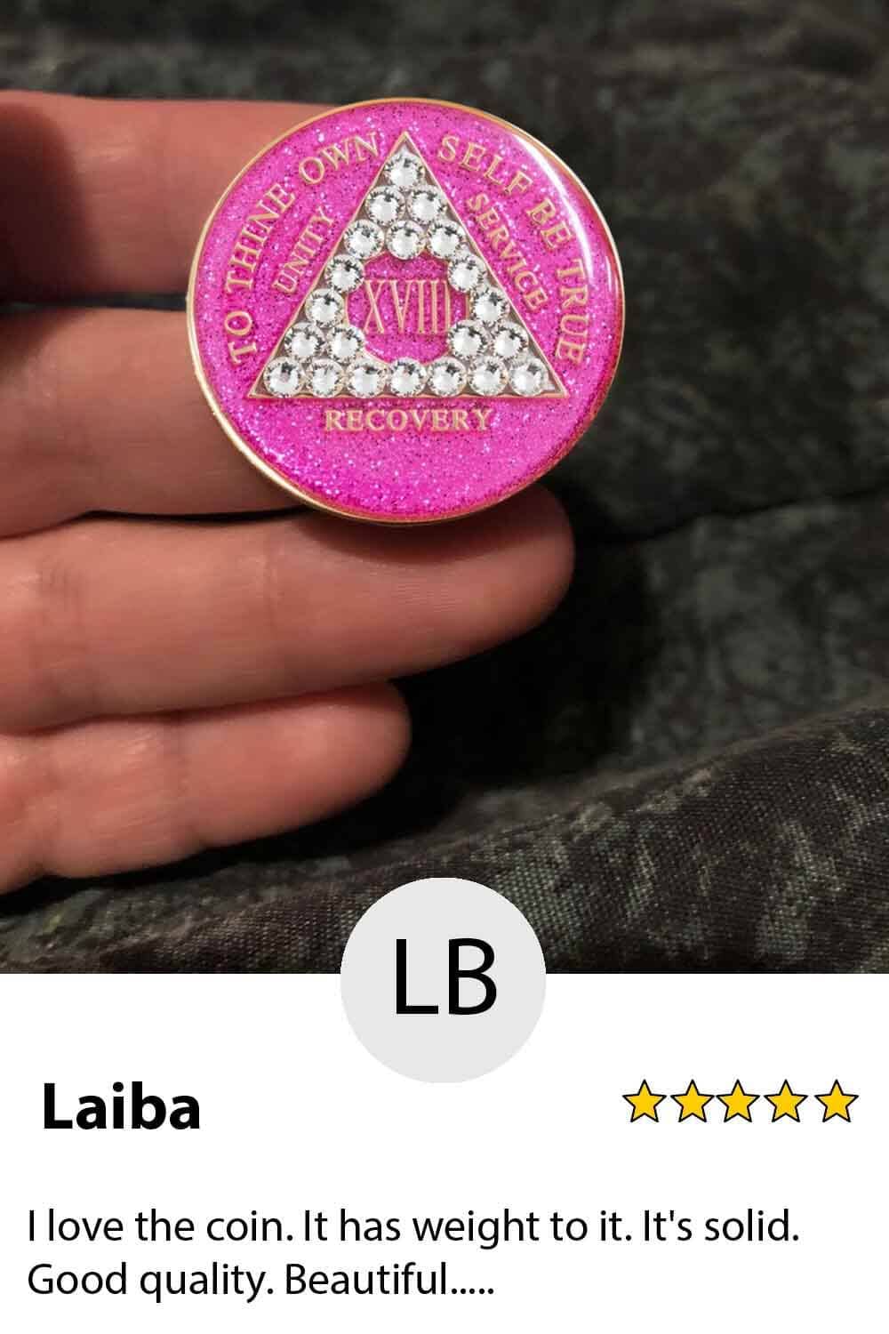 A pink coin with diamonds on it is held in someone 's hand.