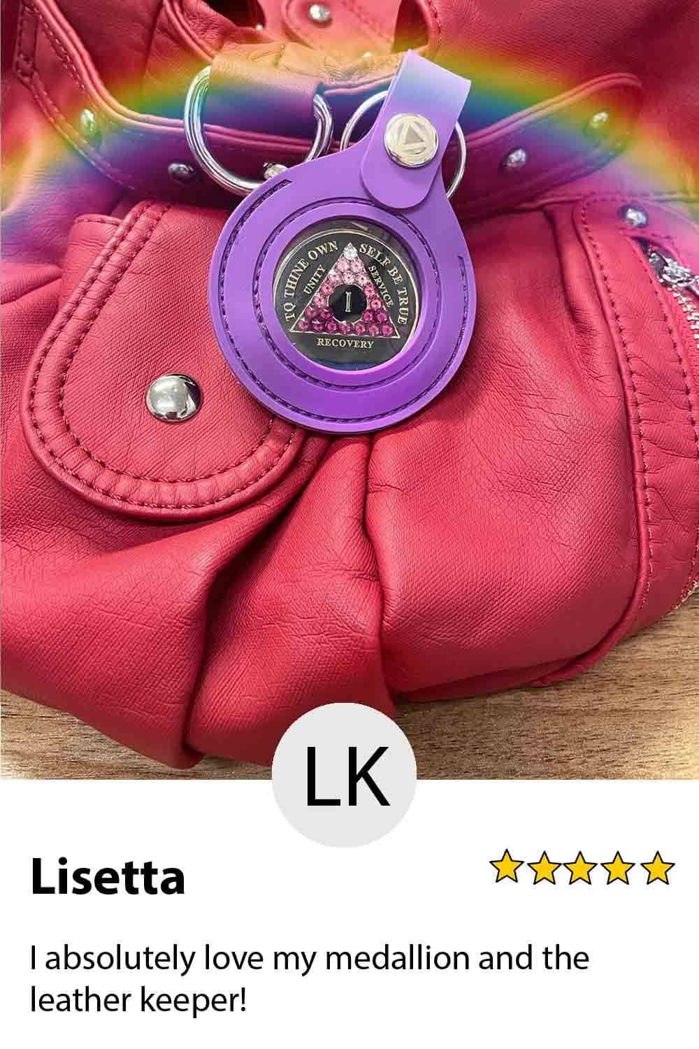 A pink purse with a purple bag charm on it.